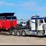 red heavy machinery being hauled by truck