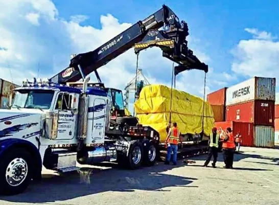 heavy cargo lifted on to a flatbed diesel truck ready for transport